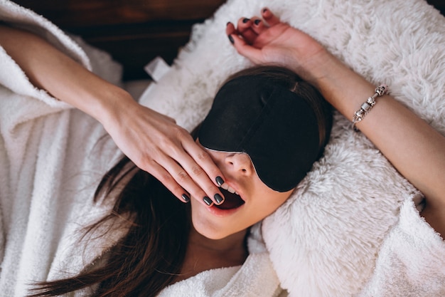 Бесплатное фото Женщина в кровати носить маску сна