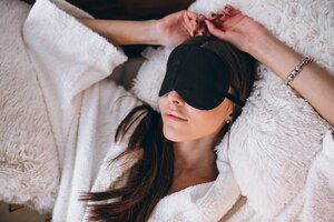Бесплатное фото Женщина в кровати носить маску сна
