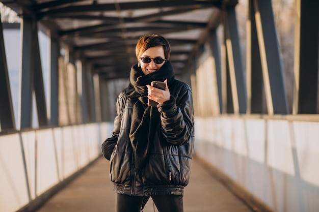 Бесплатное фото Женщина в черной куртке идет по мосту