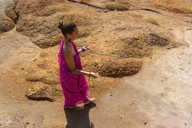 동양인 복장을 한 여성이 측량법으로 사막 지역에서 물을 찾고 있다