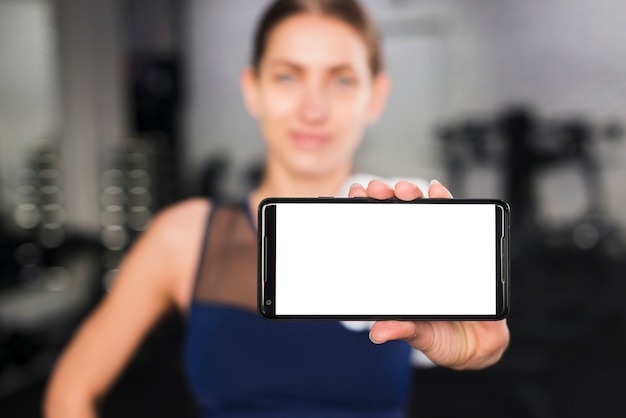 Бесплатное фото Женщина в тренажерном зале с шаблоном смартфона