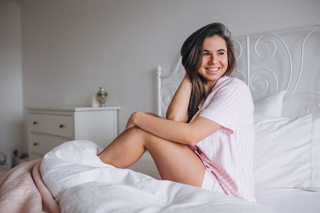 Бесплатное фото Женщина в пижаме сидит на кровати
