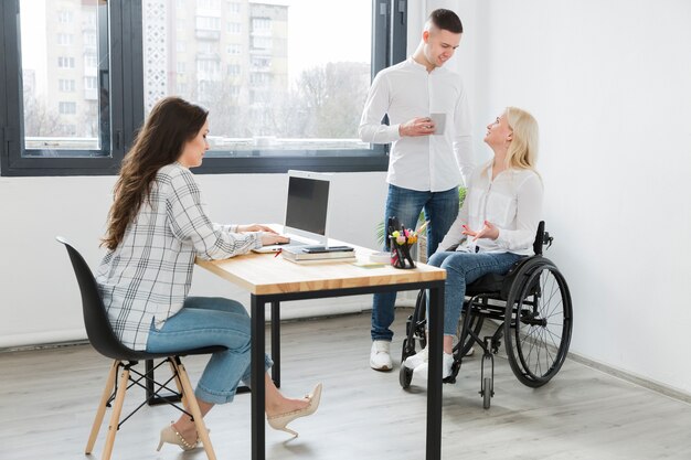 Бесплатное фото Женщина в инвалидной коляске в офисе с коллегами