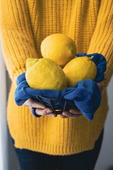 신선한 레몬을 들고 노란색 스웨터를 입은 여자