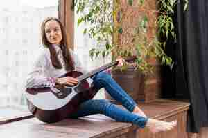 Free photo woman indoors playing the guitar