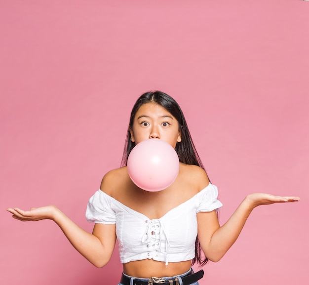 Foto gratuita la donna gonfia un palloncino rosa