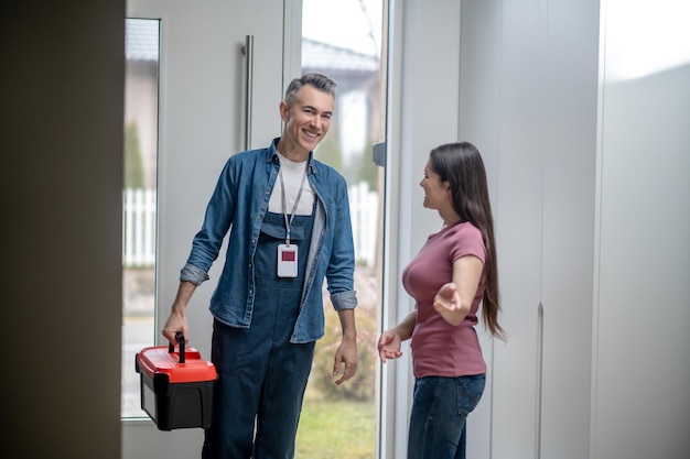 Woman inviting man to the house with tools