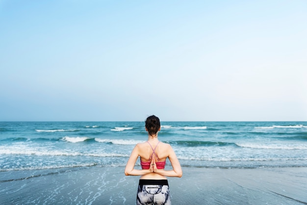 A woman is doing a yoga at the beach