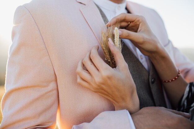 Woman is fixing a stylish bridal buttonhole to a man