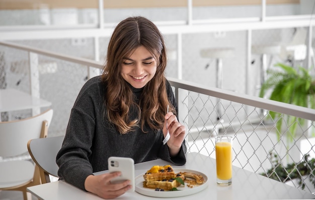 A woman is having breakfast with belgian waffles and orange juice