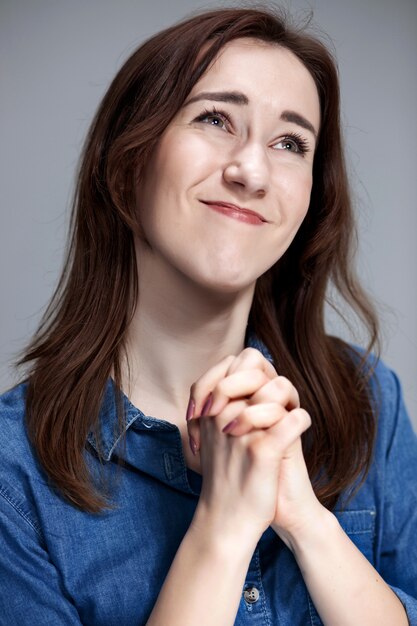 Woman is looking imploring over gray wall