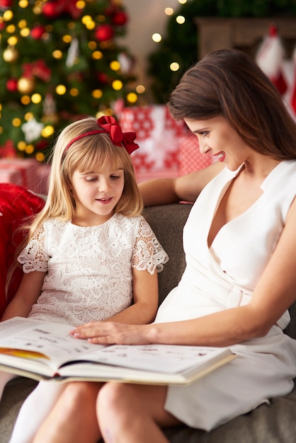 Woman is reading book with girl