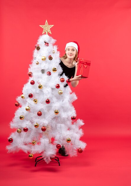 A woman is standing next to the Christmas tree