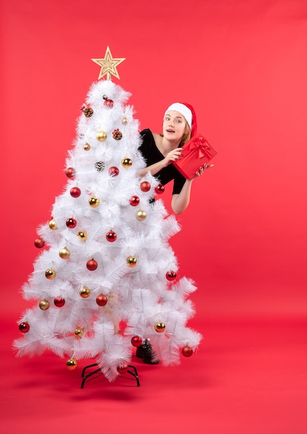 A woman is standing next to the Christmas tree