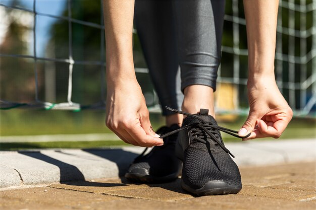 Woman is tying summer sneakers near the football gates