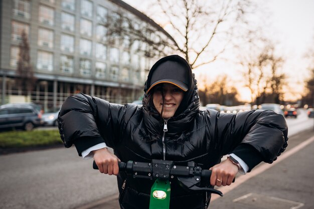 Woman in a jacket on an electric scooter in an autumn city. Riding on electric vehicles in cold weather.