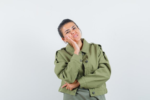 woman in jacket, t-shirt holding hand on cheek and looking dreamy