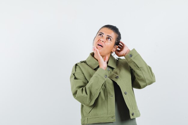 woman in jacket, t-shirt posing while standing and looking pensive