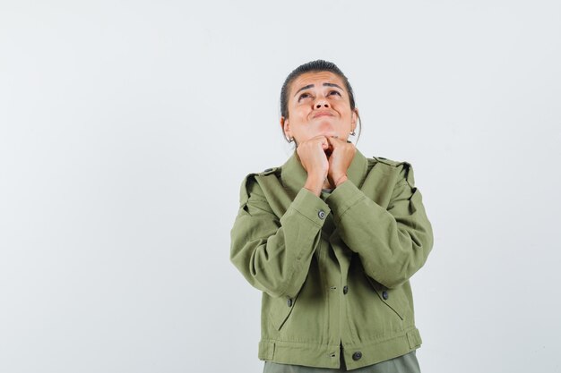 woman in jacket, t-shirt propping chin on fists and looking hopeful