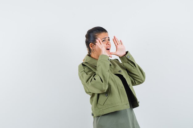 woman in jacket, t-shirt shouting or announcing something and looking anxious