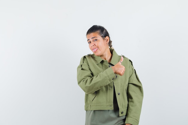 woman in jacket, t-shirt showing thumb up and looking confident