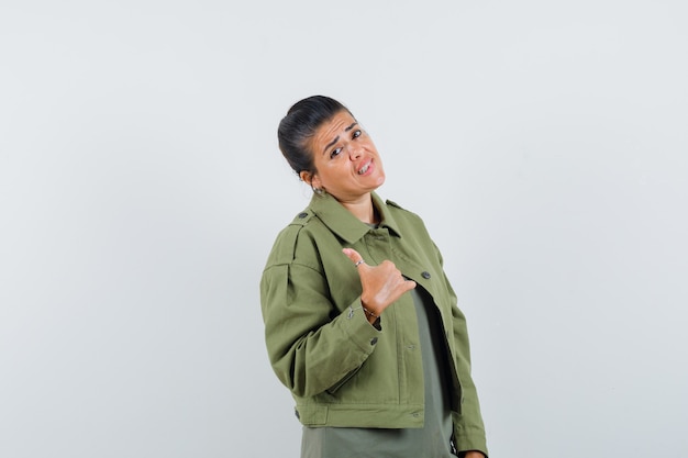 woman in jacket, t-shirt showing thumb up and looking hesitant