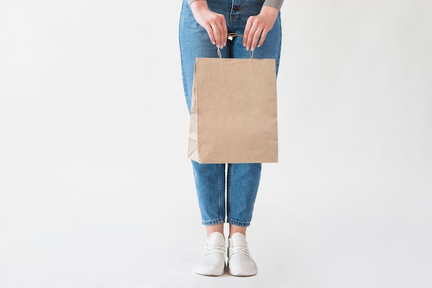 Woman in jeans holding paper bag with groceries