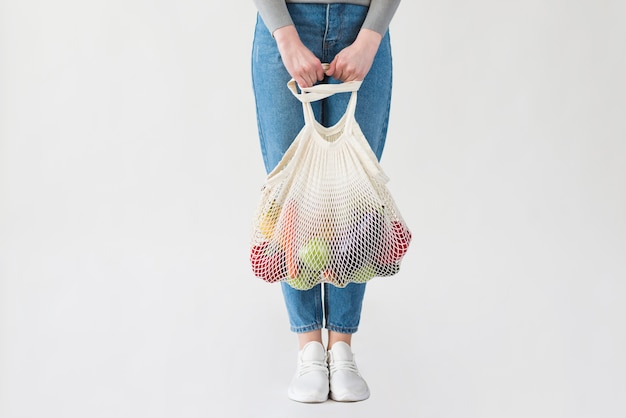 Foto gratuita donna in jeans che tengono borsa riutilizzabile con generi alimentari