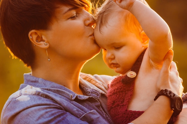 Free photo woman in jeans jacket kisses little girl in her arms