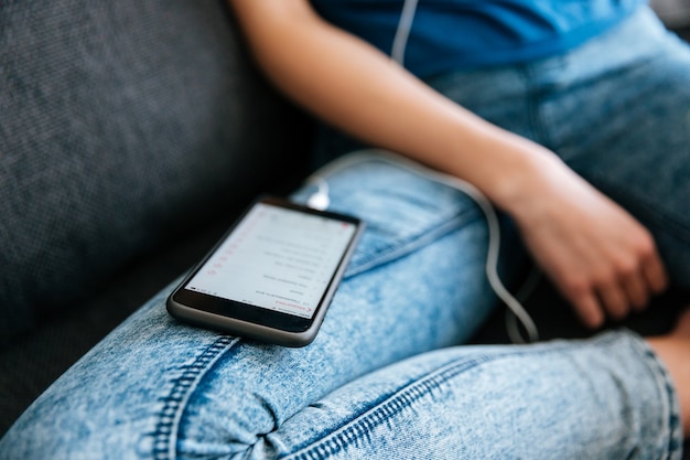 Женщина в джинсах слушает музыку с мобильного телефона