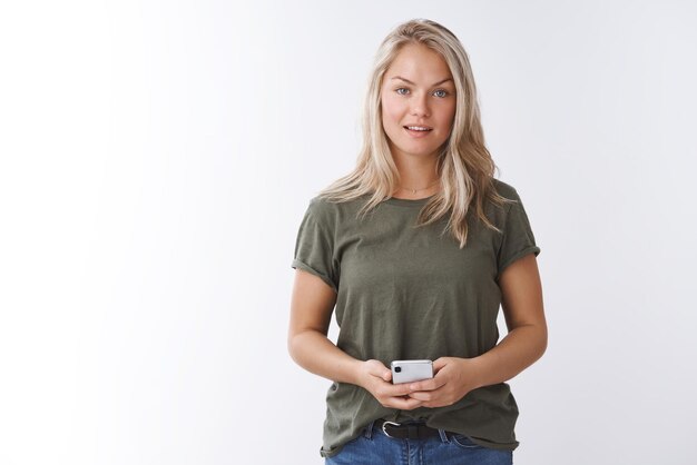 woman journalist recording conversation via smartphone holding mobile phone near chest and gazing at camera