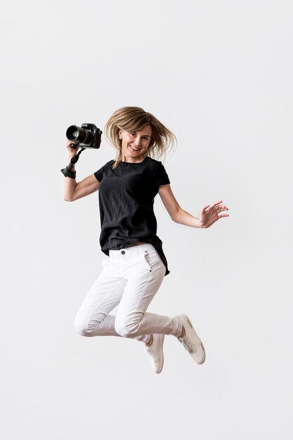 Woman jumping and holding a camera