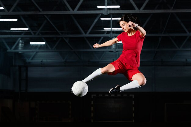 Женщина прыгает, чтобы пнуть мяч