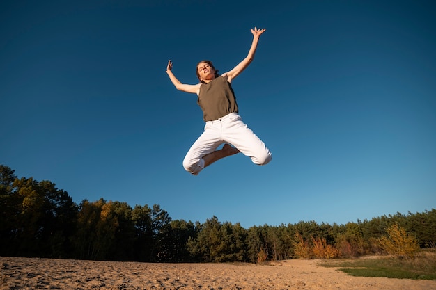 Free photo woman jumping in nature full shot