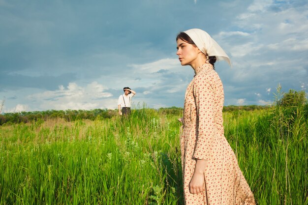 woman in kerchief and man in hat on green meadow