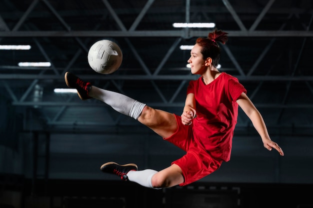 Donna che dà dei calci al pallone da calcio