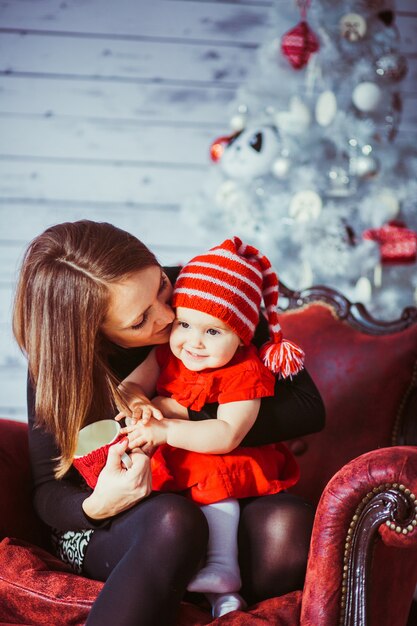 Woman kisses her daughter sitting on red leather armchair