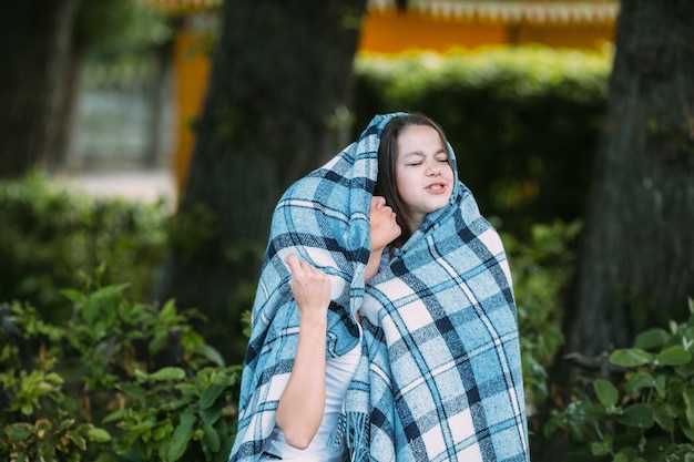 Woman kissing girl wrapped in plaid