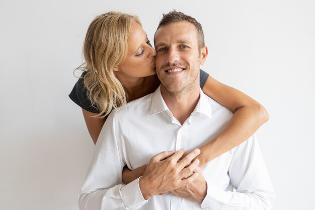 Woman kissing happy husband on cheek