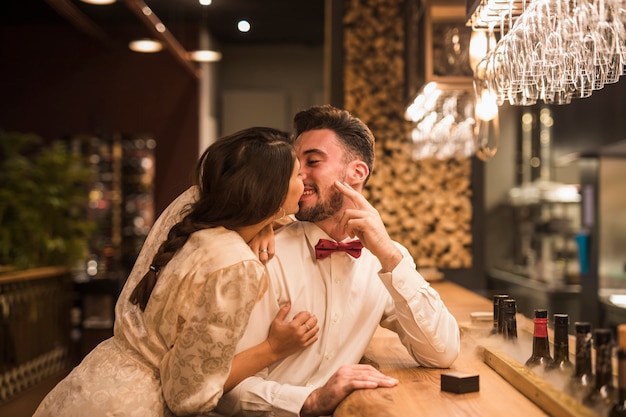 Woman kissing happy man at bar counter