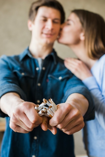 Woman kissing her boyfriend broken bundle of cigarettes