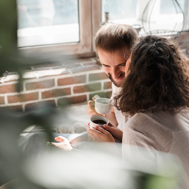 Woman kissing her boyfriend holding cup of coffee