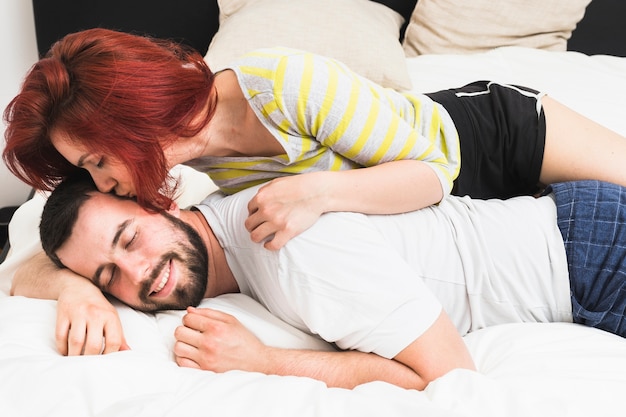 Женщина целует мужа на кровати