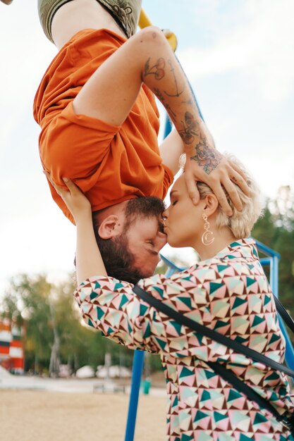 Woman kissing her man while he hangs with head down sky 