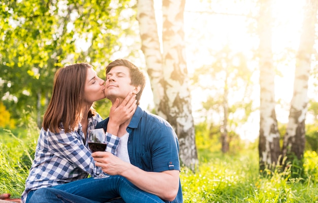 Woman kissing man on cheek amid birches