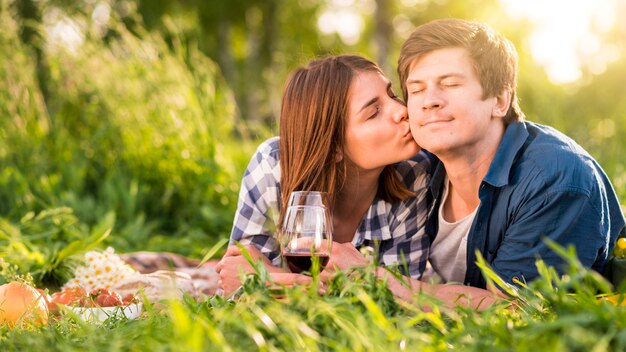 Woman kissing man on cheek in forest