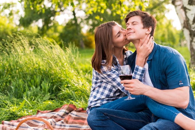 Женщина целует мужчину в щеку во время пикника