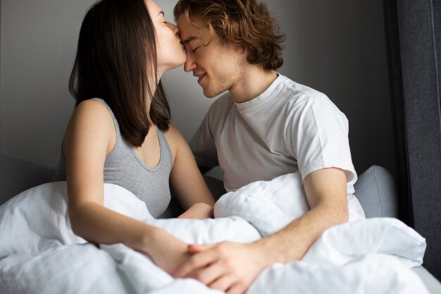 woman kissing man's forehead while holding hands