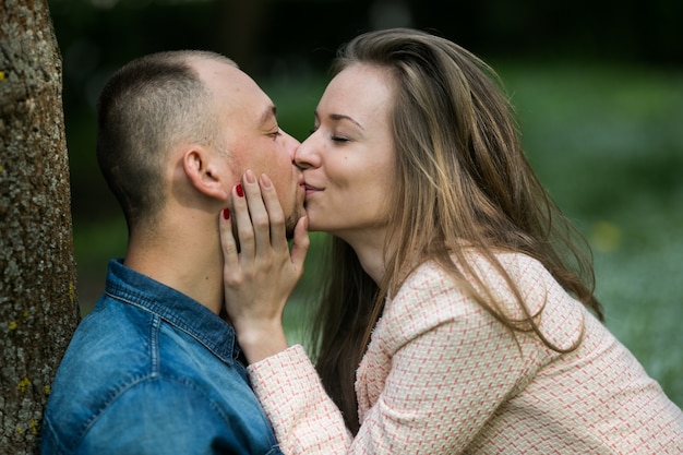 "Woman kissing man sitting outside"