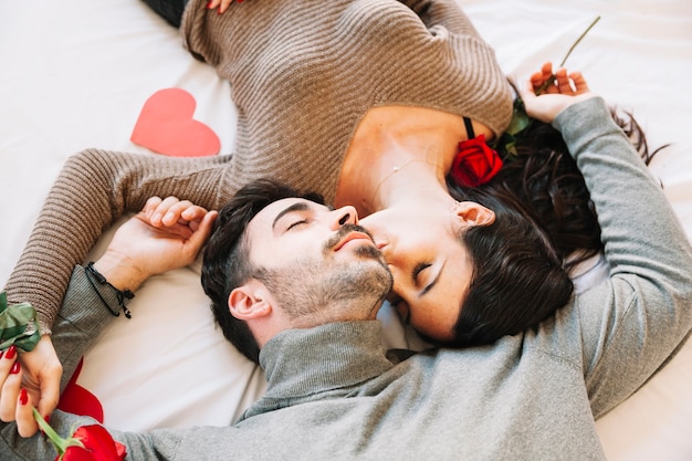 Free photo woman kissing man on white sheet